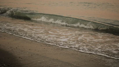 Onda che si infrange dolcemente sulla spiaggia sabbiosa al tramonto