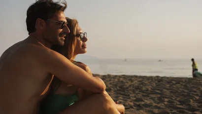 Coppia che si abbraccia e guarda il tramonto sulla spiaggia