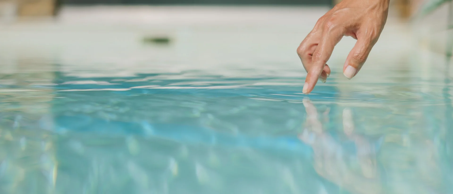 Mano che tocca delicatamente l'acqua chiara di una piscina