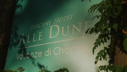 Cartello verde con scritta Tuscany Hotel Alle Dune Vacanze di Charme