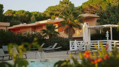 Piscina con sedie a sdraio e vegetazione davanti a una casa arancione