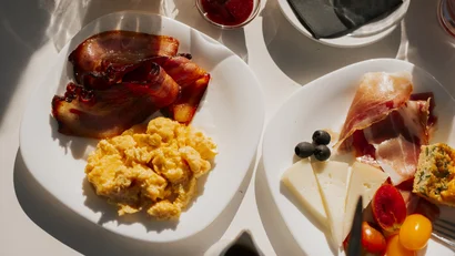 Colazione con uova strapazzate, bacon, formaggi, prosciutto, olive e pomodori