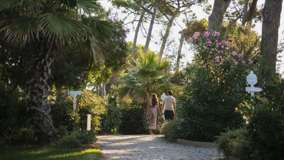 Coppia che passeggia su un sentiero acciottolato circondato da vegetazione e fiori